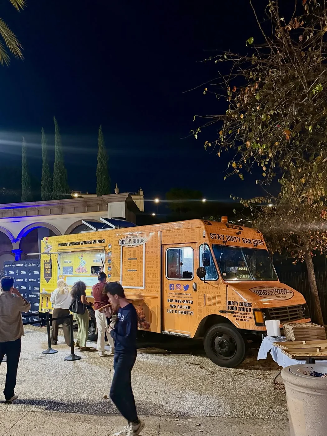The orange Dirty Birds truck serving at a night-time gathering